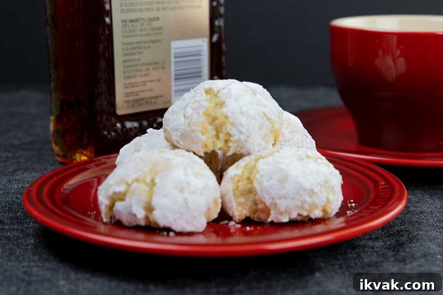 Amaretti cookies stacked on a red plate with a red coffee cup in the background.