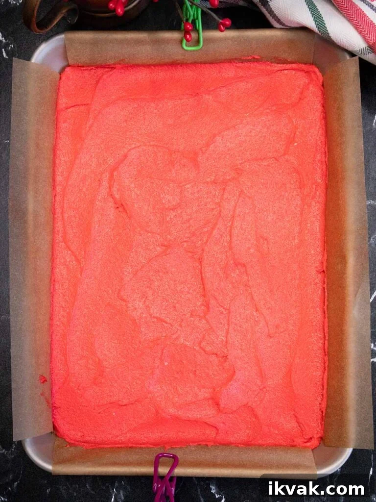 Red cookie dough in the parchment paper lined pan.