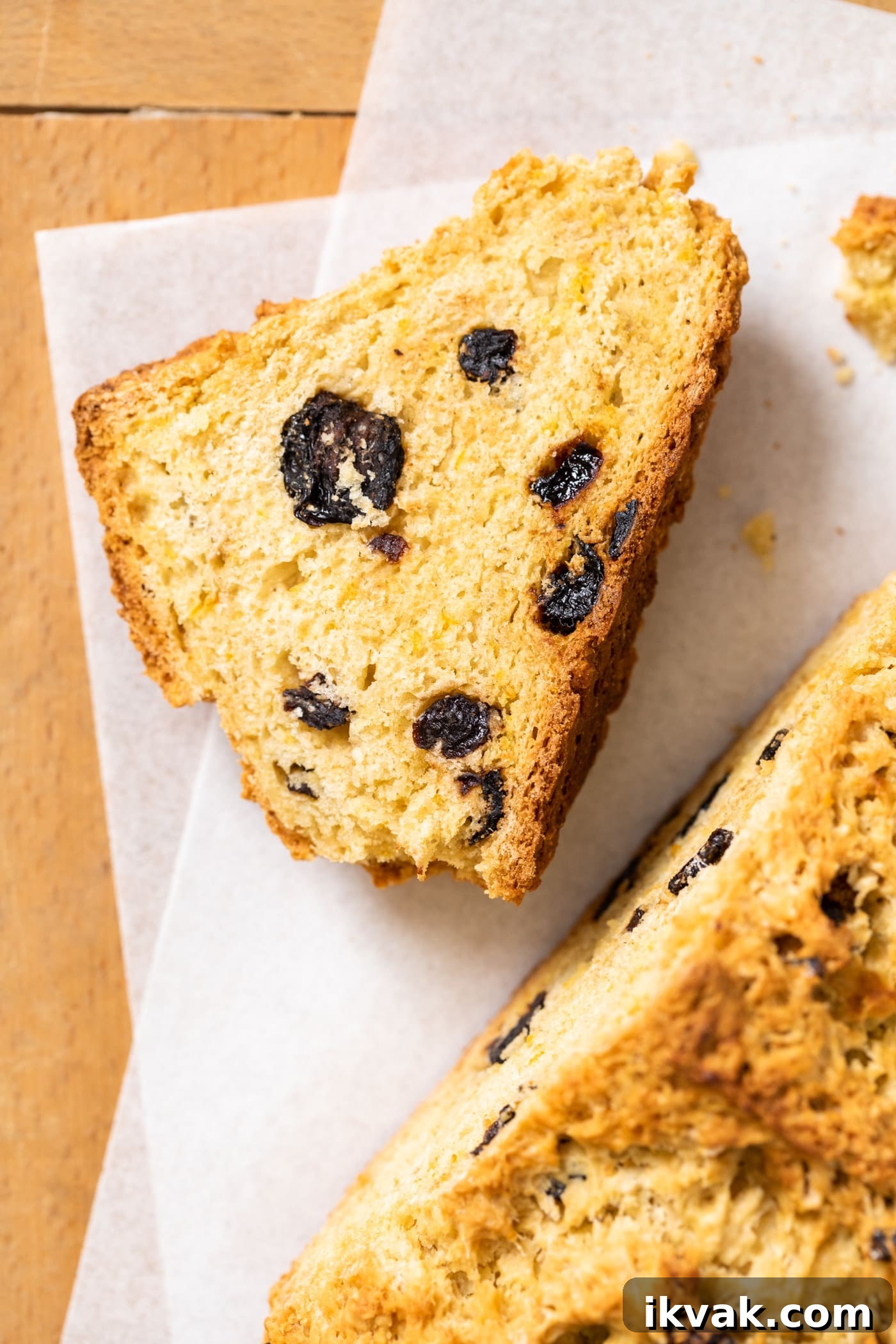 Orange Cherry Irish Soda Bread Recipe for Zesty Homemade Loaf 3 Top down view of slice of Irish soda bread with bits of dried cherry inside sitting on white piece of parchment paper with rest of loaf to the side