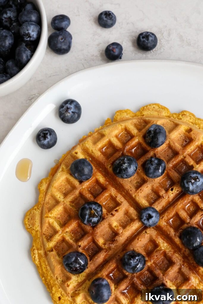 Sweet Potato Waffles served on a plate topped with maple syrup and blueberries 
