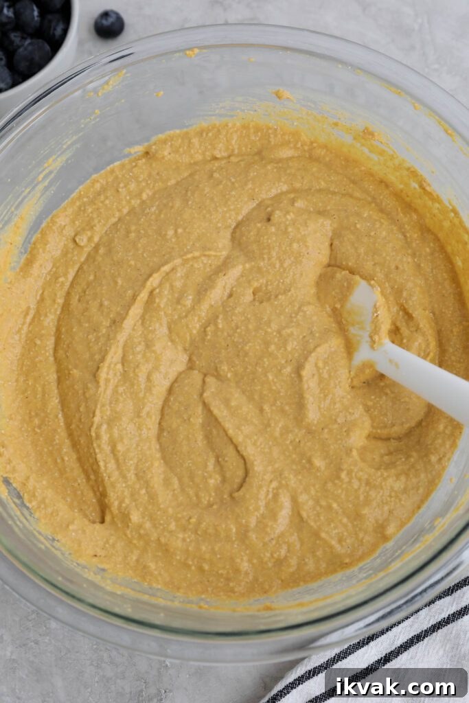 ingredients for sweet potato waffles in glass bowl with spatula 