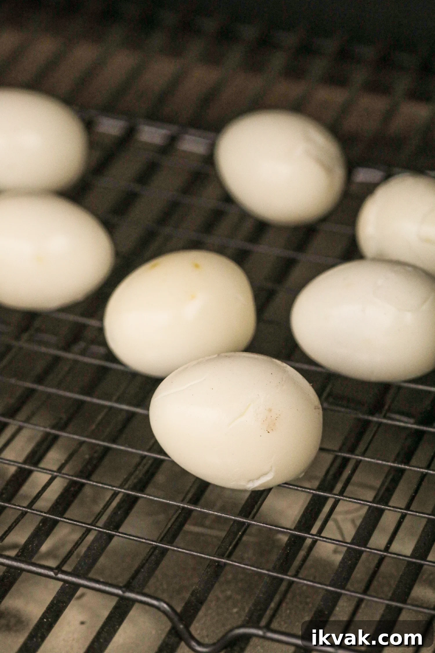 Peeled hard-boiled eggs placed on a wire rack inside a smoker.