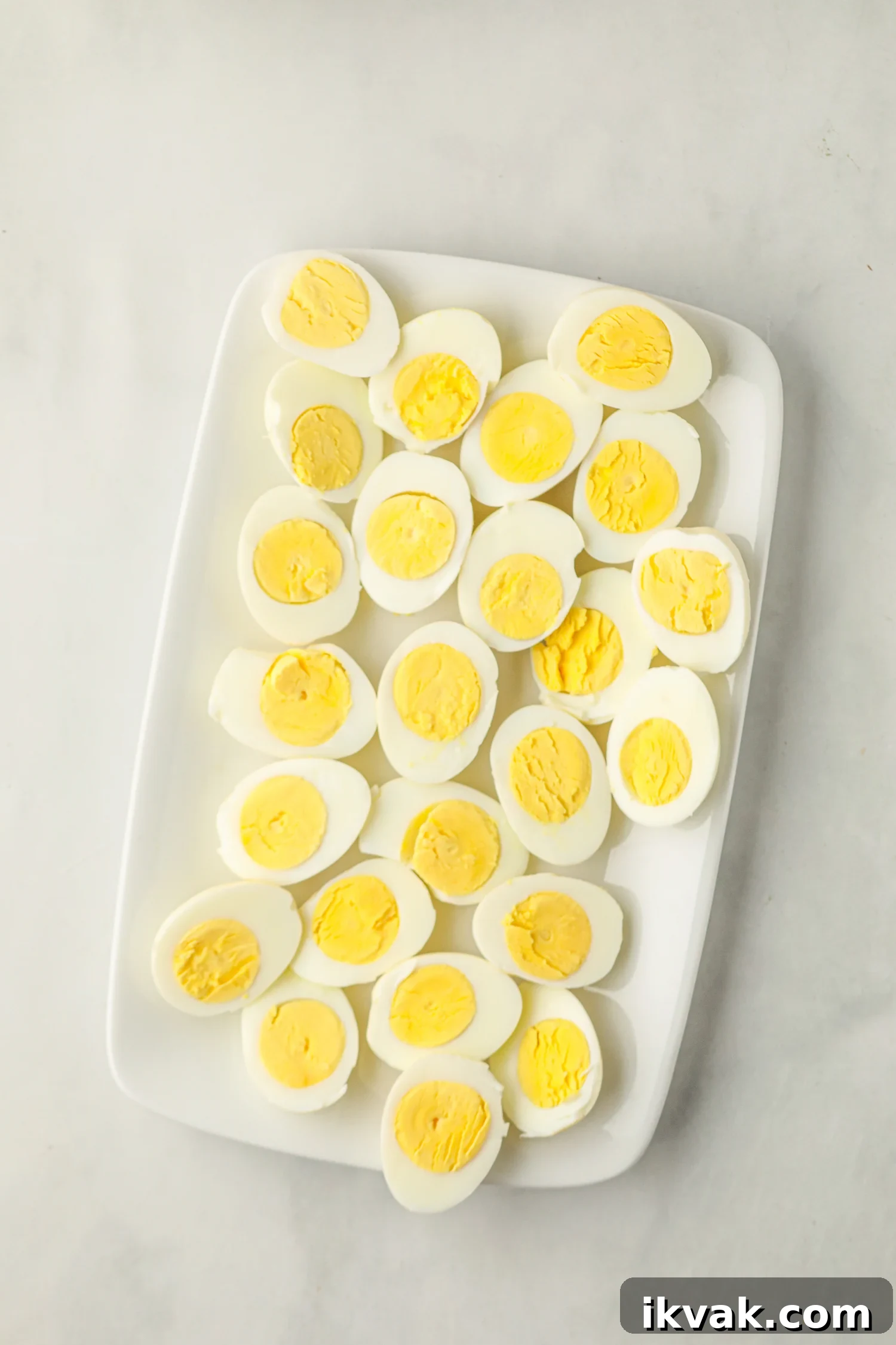 A white rectangular plate filled with smoked hard-boiled eggs that have been cut in half.