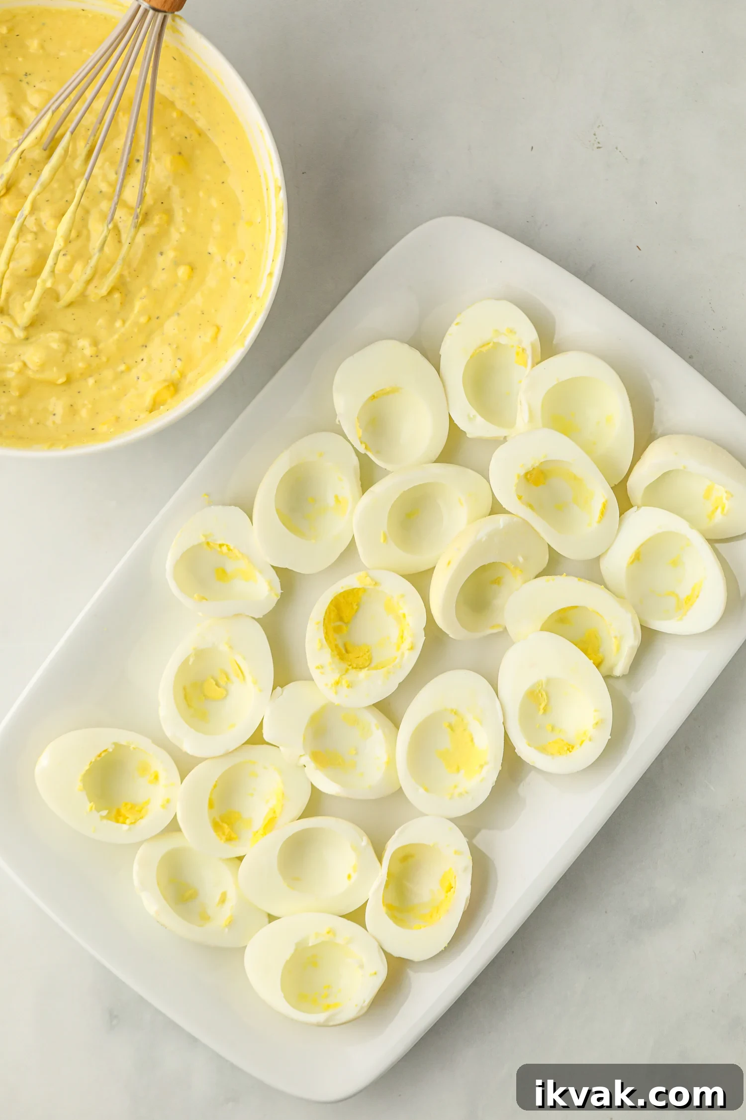 A white rectangular plate filled with halved smoked eggs with their yolks removed, leaving hollow centers.