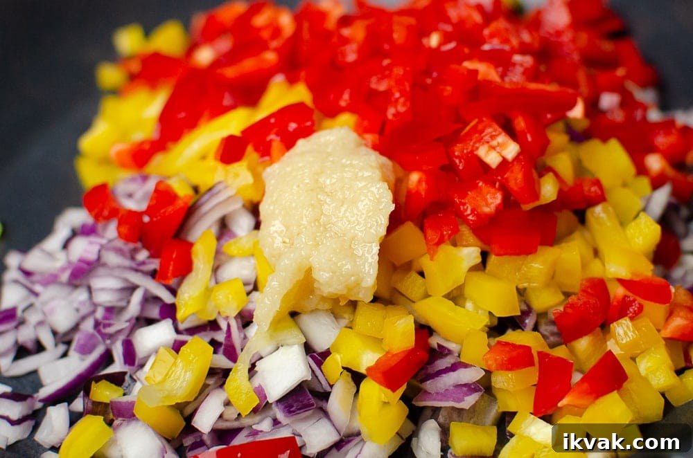 Chopped red onion,red pepper,yellow pepper and garlic all in a pan ready to cook