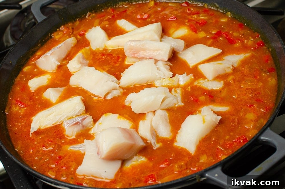 Adding the pieces of haddock to spicy fish soup