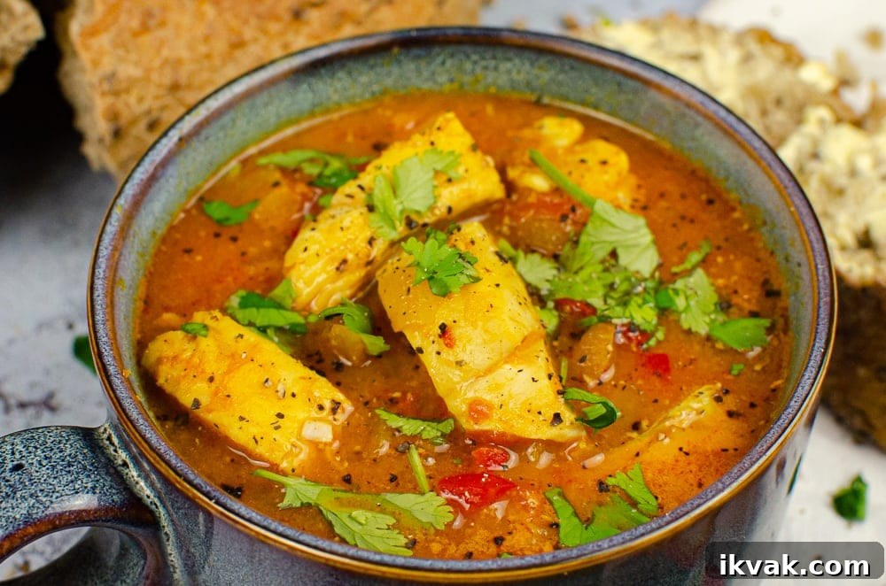 Spicy fish soup in a blue bowl with chopped coriander on top