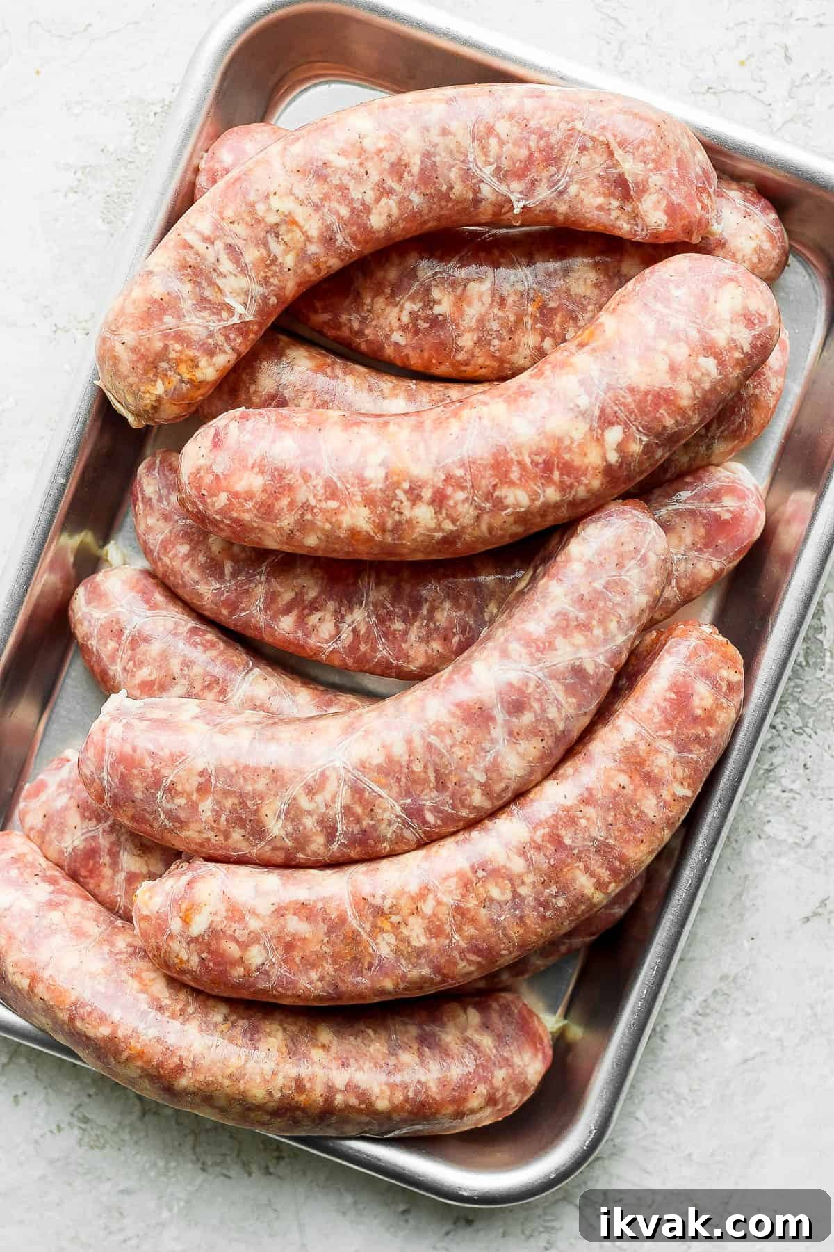 Uncooked brats on a metal tray.