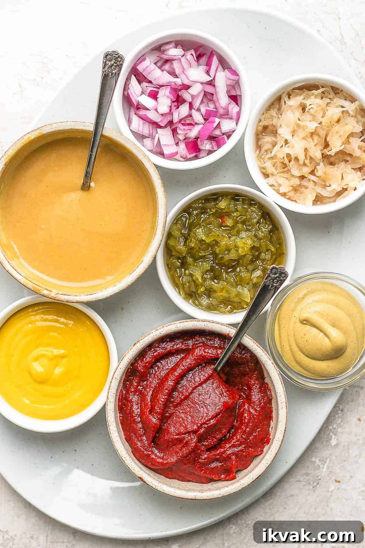 Brat toppings in small bowls on a large white plate.