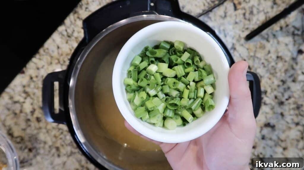 Adding scallions to the pressure cooked soup.