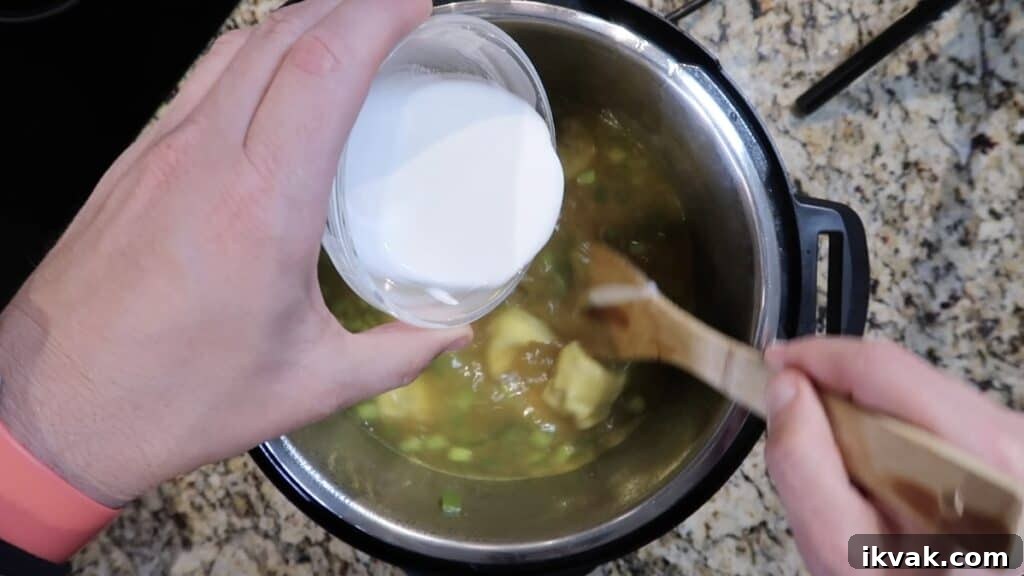 Stirring the cornstarch slurry into the soup so it thickens
