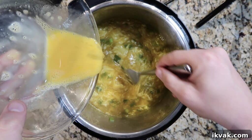 Using a large serving fork to comb through the egg white which forms egg ribbons.