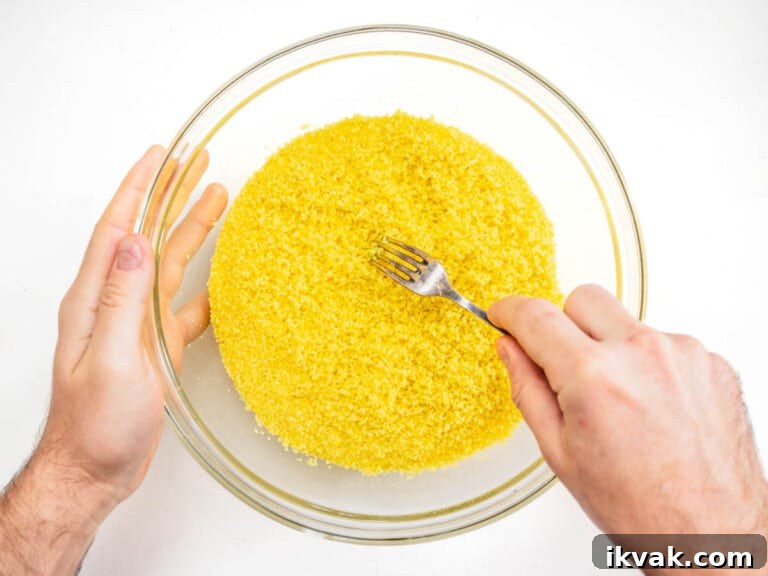 raking the couscous with a fork to fluff it up