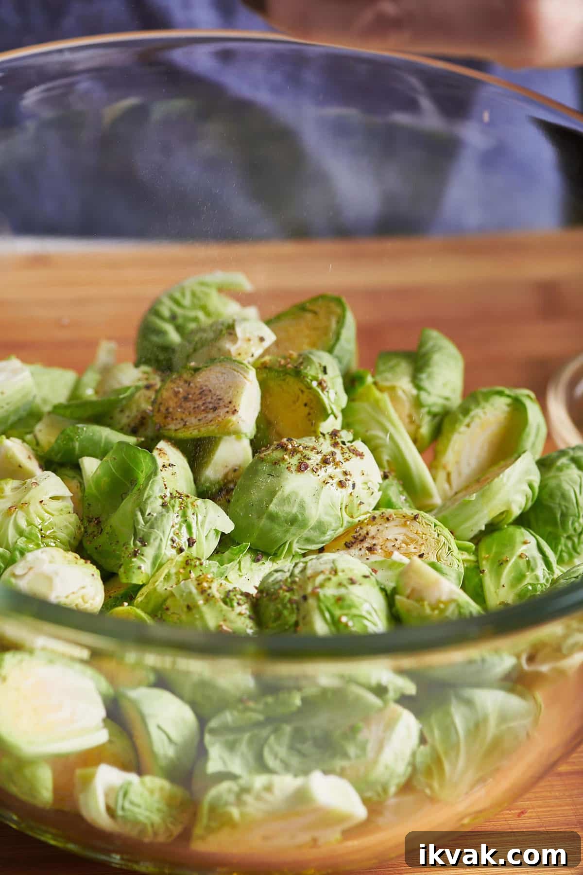 Crispy Roasted Brussels Sprouts: Simple Oven Recipe 4 Seasoned, halved brussels sprouts in a glass bowl.