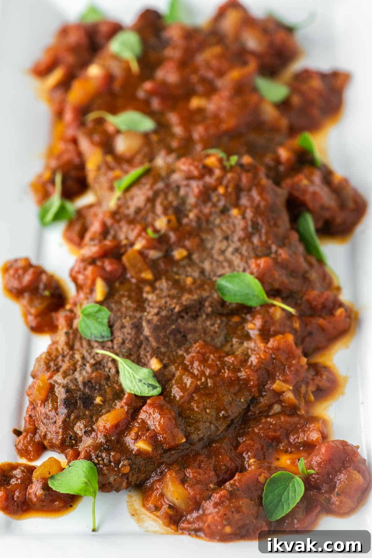 Steak alla Pizzaiola Recipe: Tender Beef in Tomato-Herb Sauce 2 Steak pizzaiola on white plate with oregano.