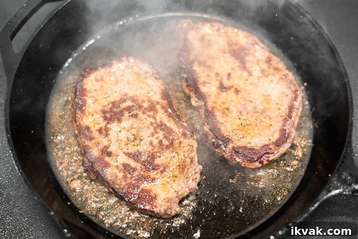 Steak alla Pizzaiola Recipe: Tender Beef in Tomato-Herb Sauce 5 Steak being cooked in skillet.