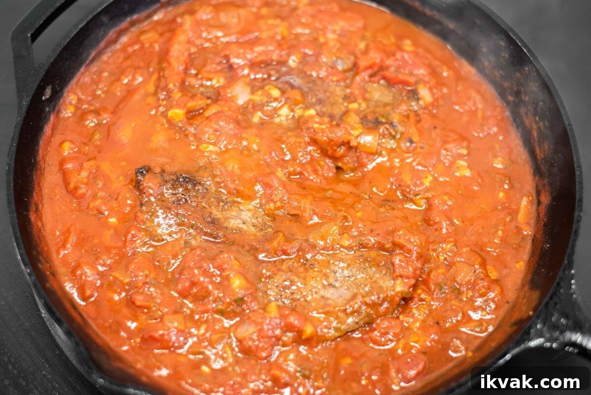 Steak alla Pizzaiola Recipe: Tender Beef in Tomato-Herb Sauce 9 Steak pizzaiola simmering in cast iron skillet.