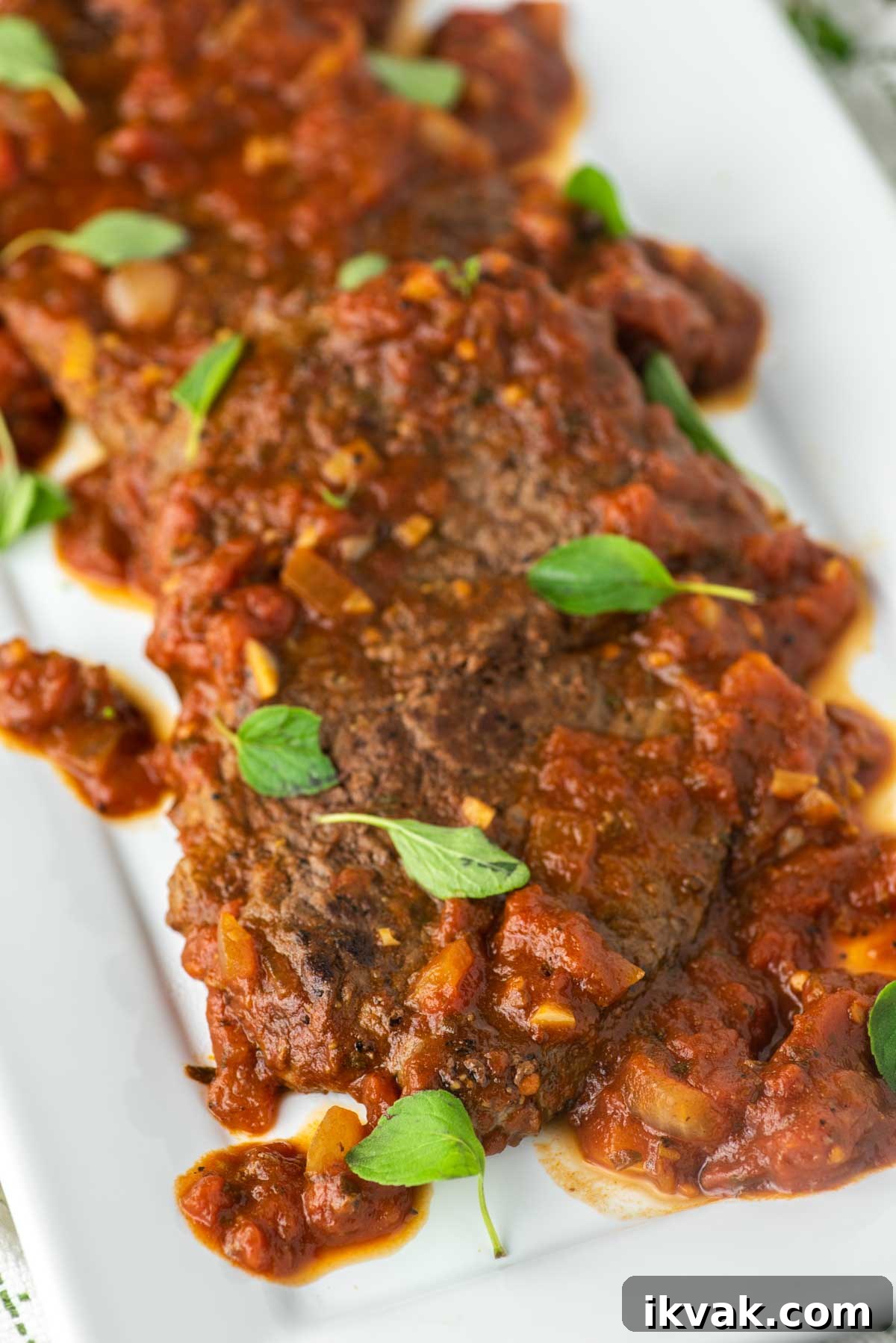 Steak alla Pizzaiola Recipe: Tender Beef in Tomato-Herb Sauce 10 Steak pizzaiola on white dish with fresh oregano.