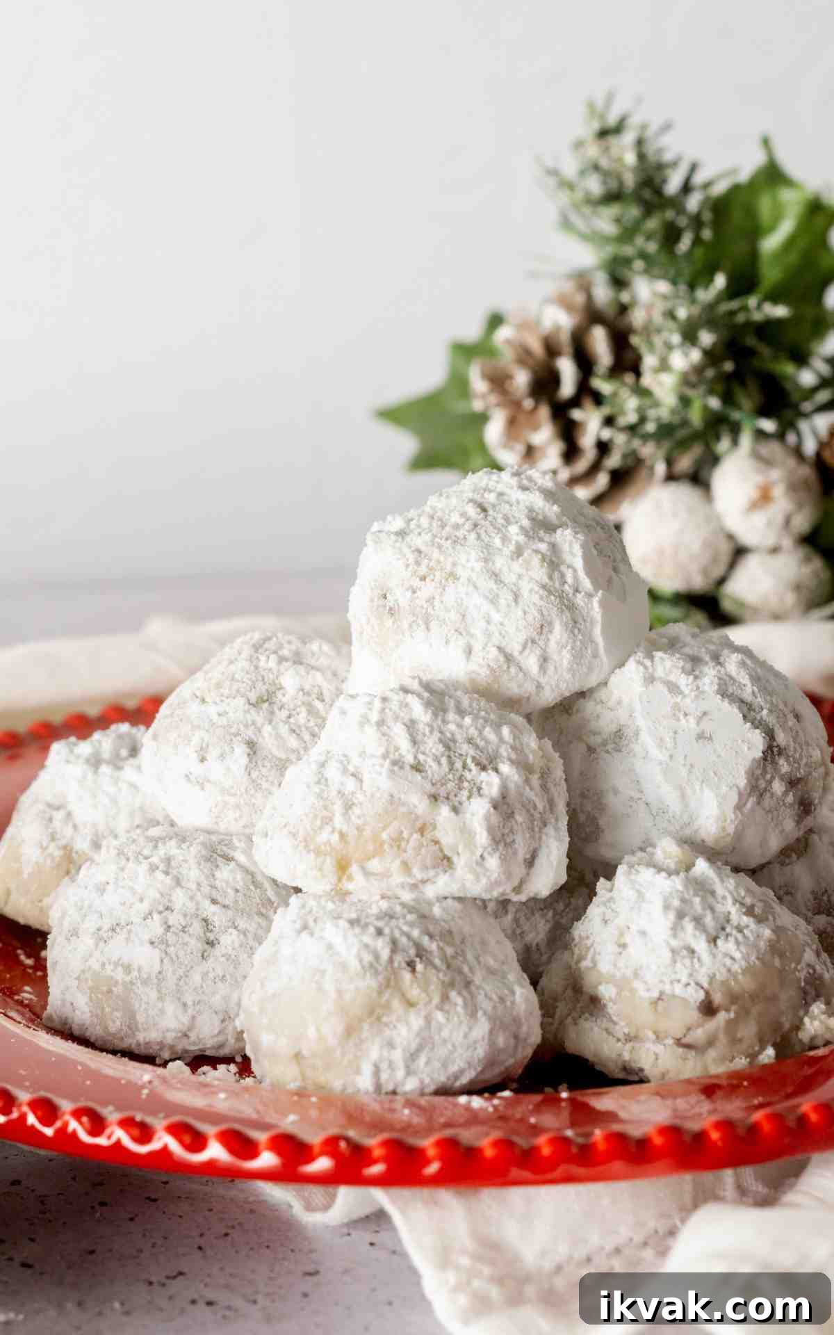A plate of snowball cookies with chocolate chips on a red plate.