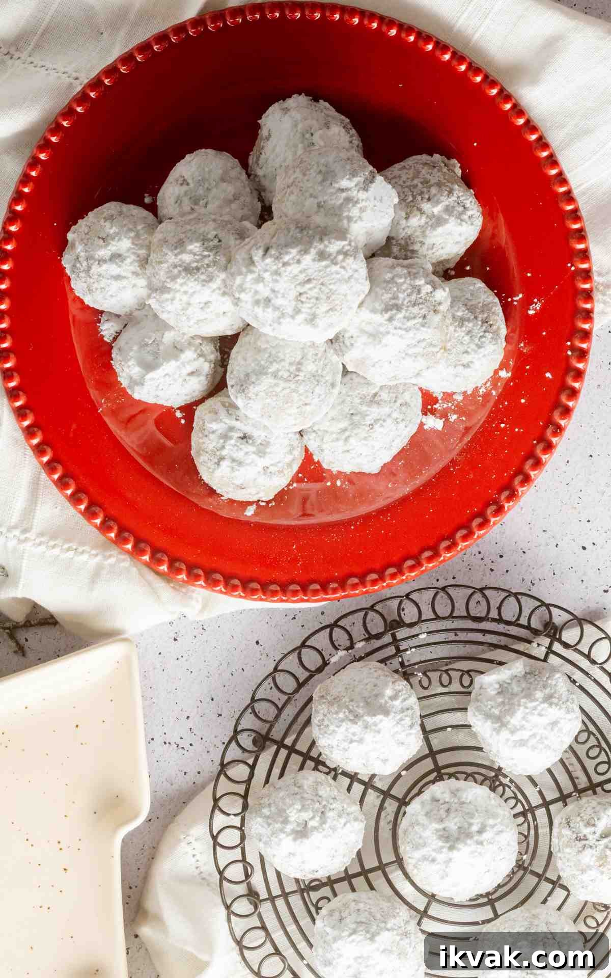 Overhead photo of snowball cookies on a plate and a wire rack.