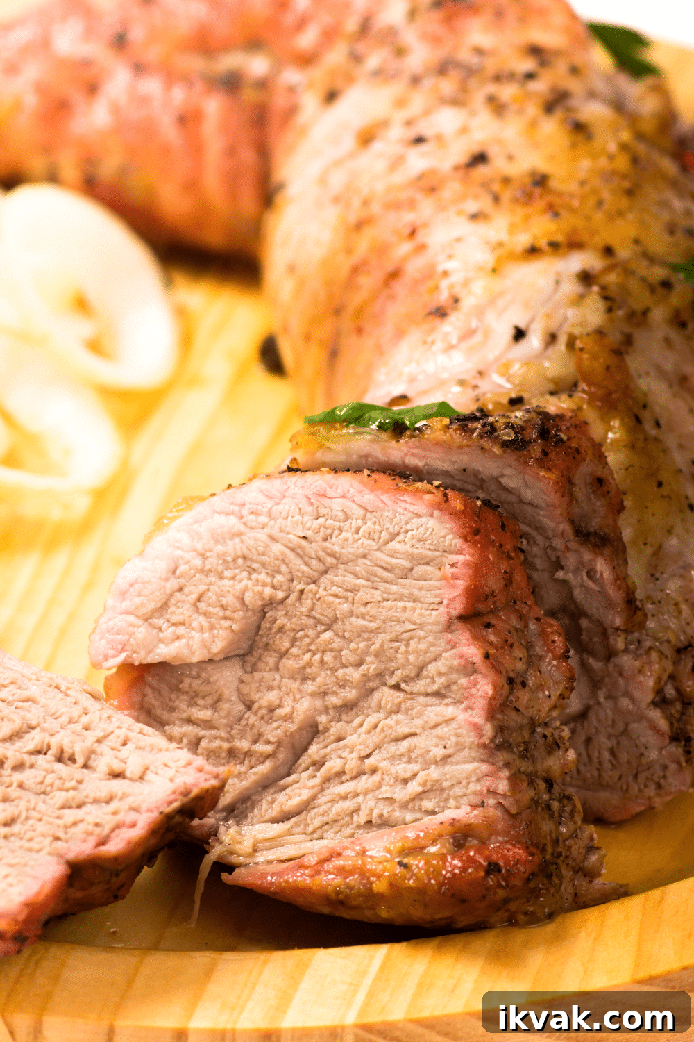 pork tenderloin sliced on a cutting board with onions