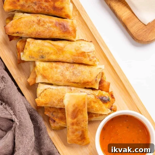 An overhead image of vegan egg rolls arranged on a serving dish with sweet chili sauce on the side.