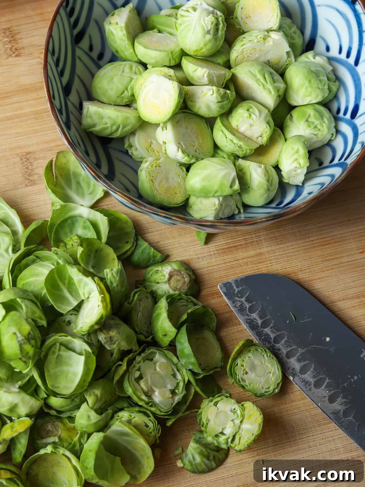 Photo of a bowl of prepped sprouts on a chopping board with the peelings and a knife in the foreground.