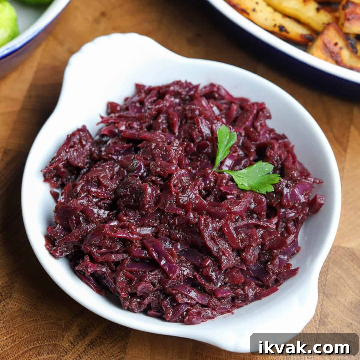 Photo of a white dish filled with braised red cabbage on a wooden table top.