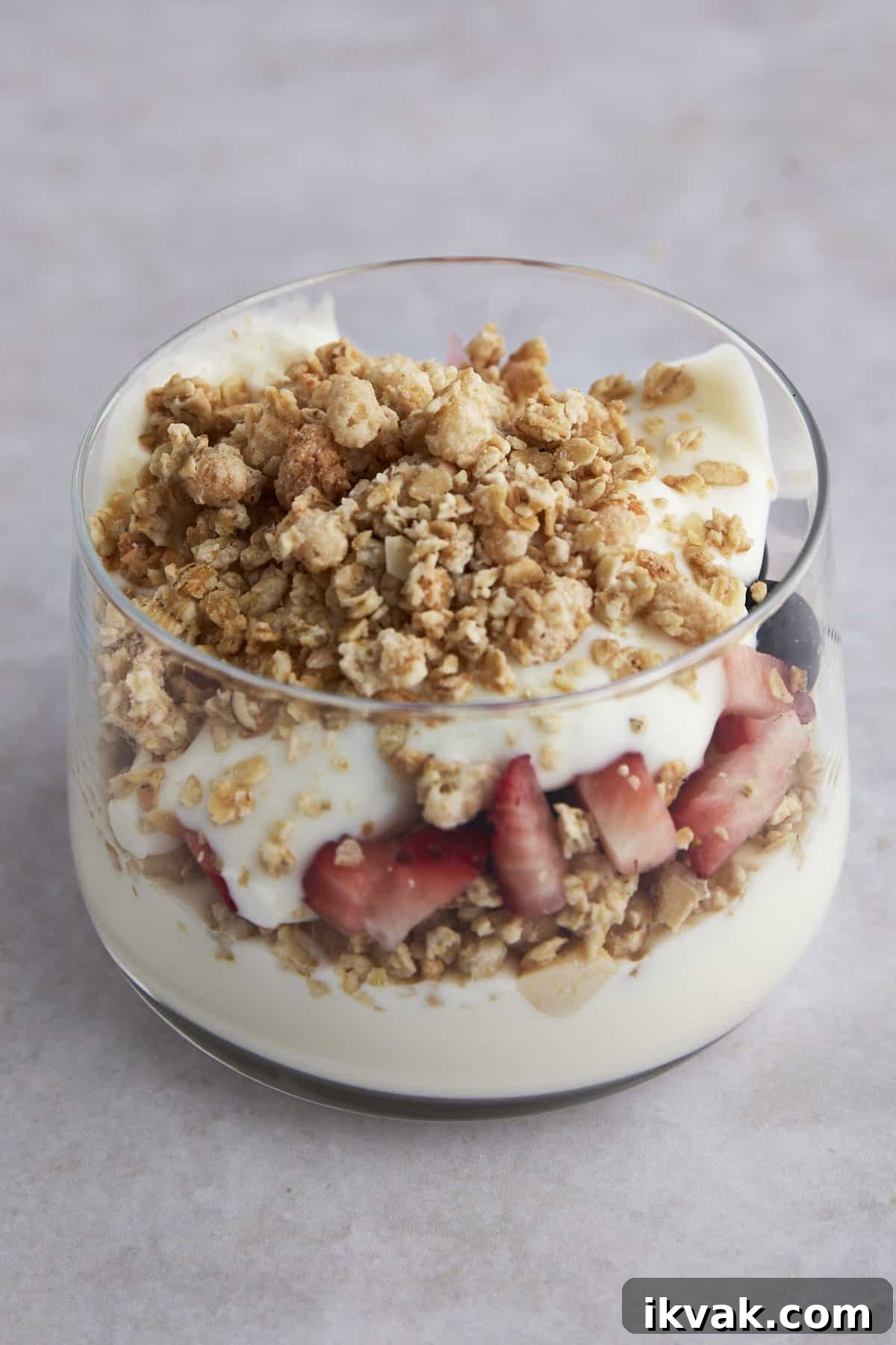 Side view of a fruit and yogurt parfait with yogurt, strawberries and granola. 