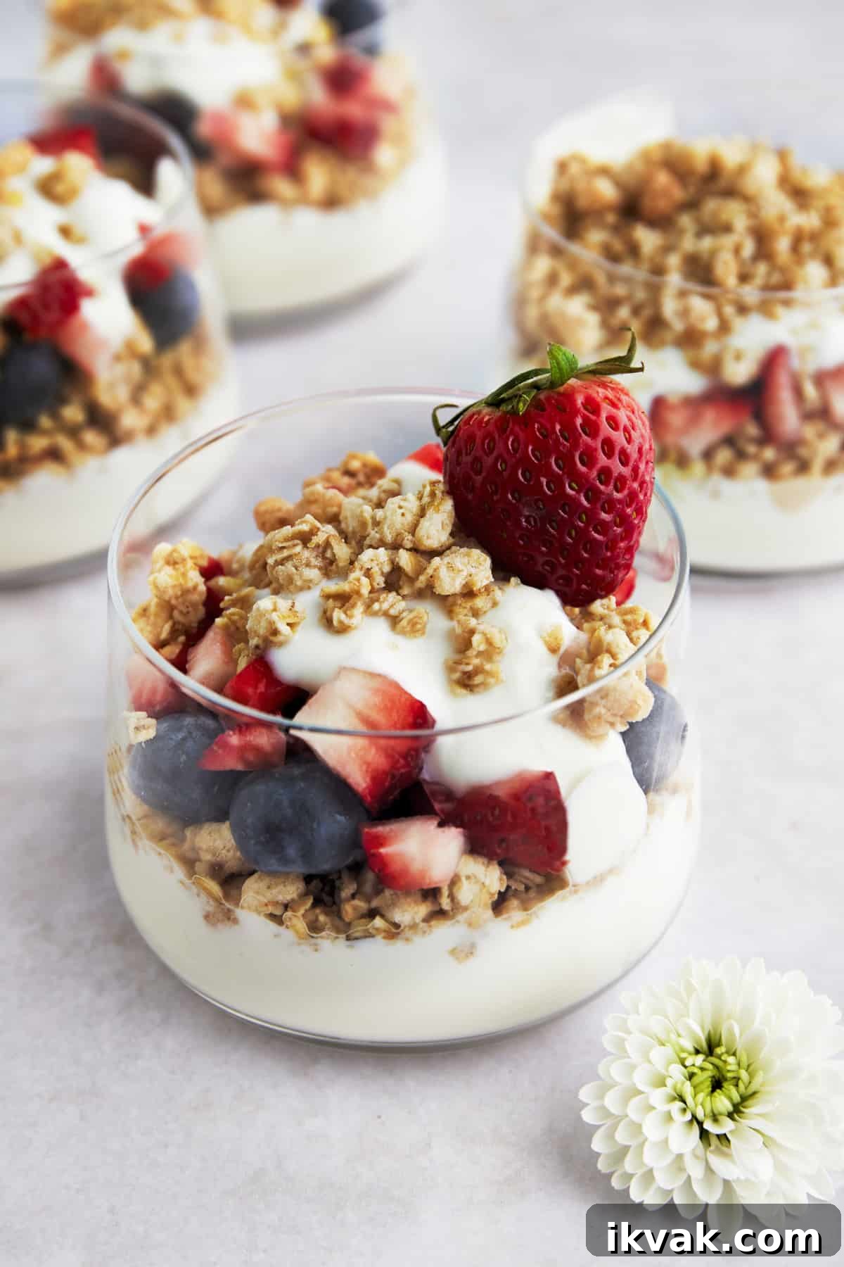 A fruit an yogurt parfait with granola, blueberries, strawberries, and honey. 