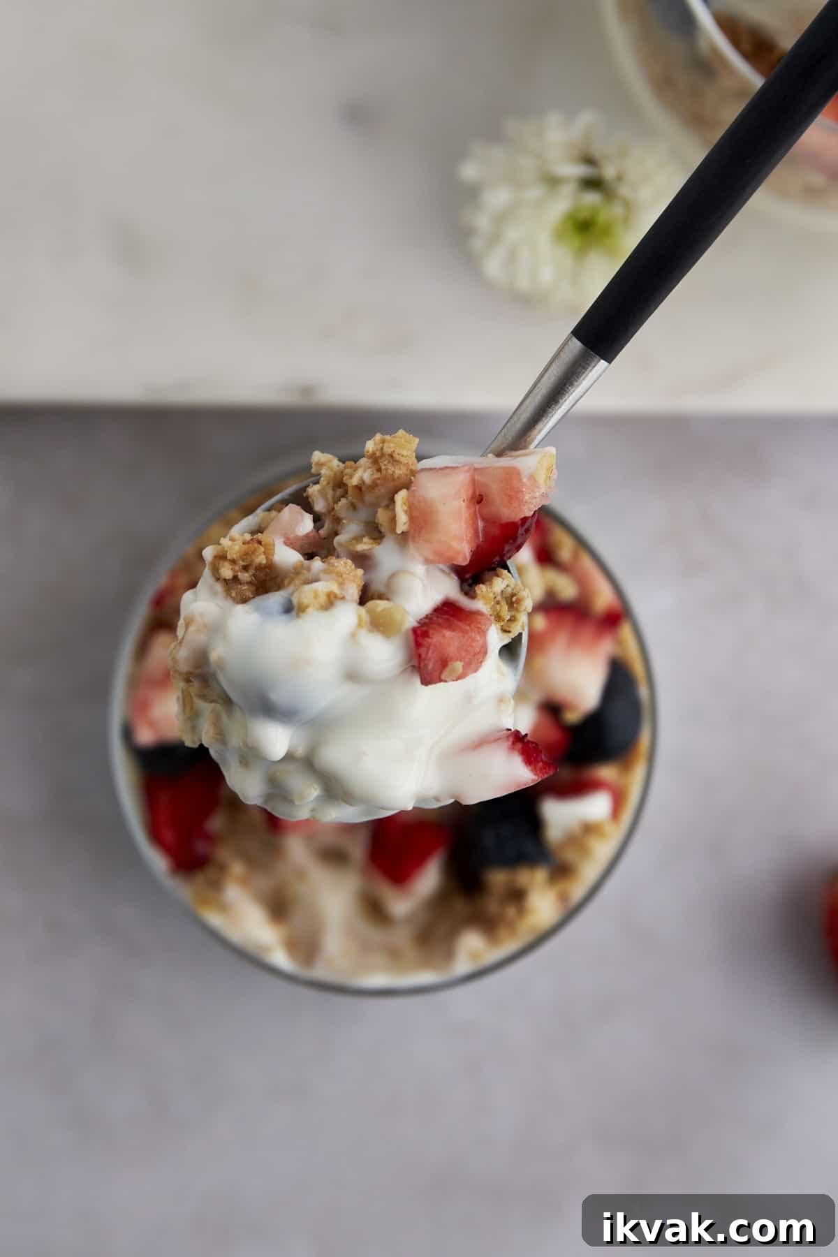 A spoonful of a yogurt parfait with granola, blueberries, and strawberries. 