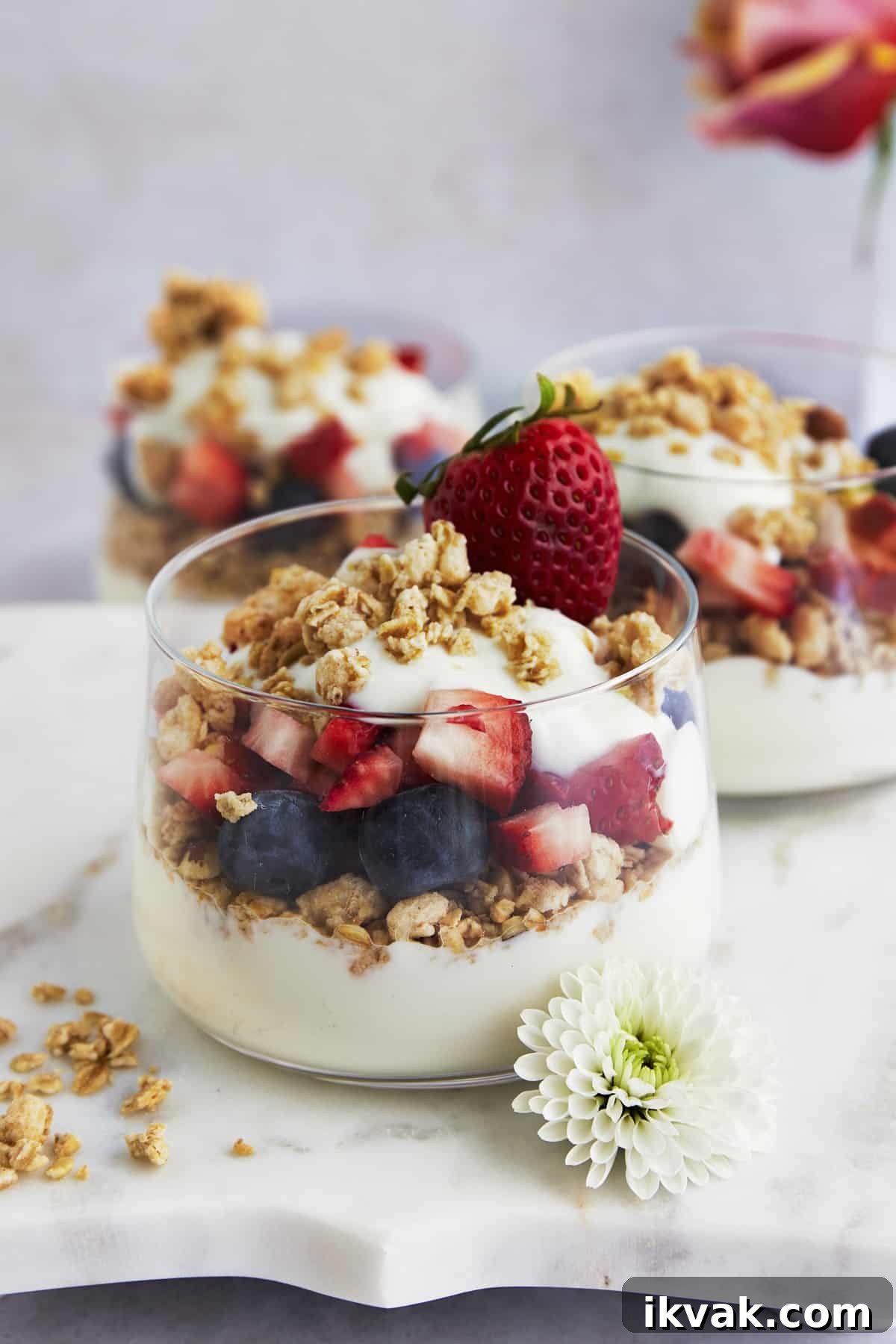 Three jars of fruit and yogurt parfait with blueberries, strawberries, and granola.