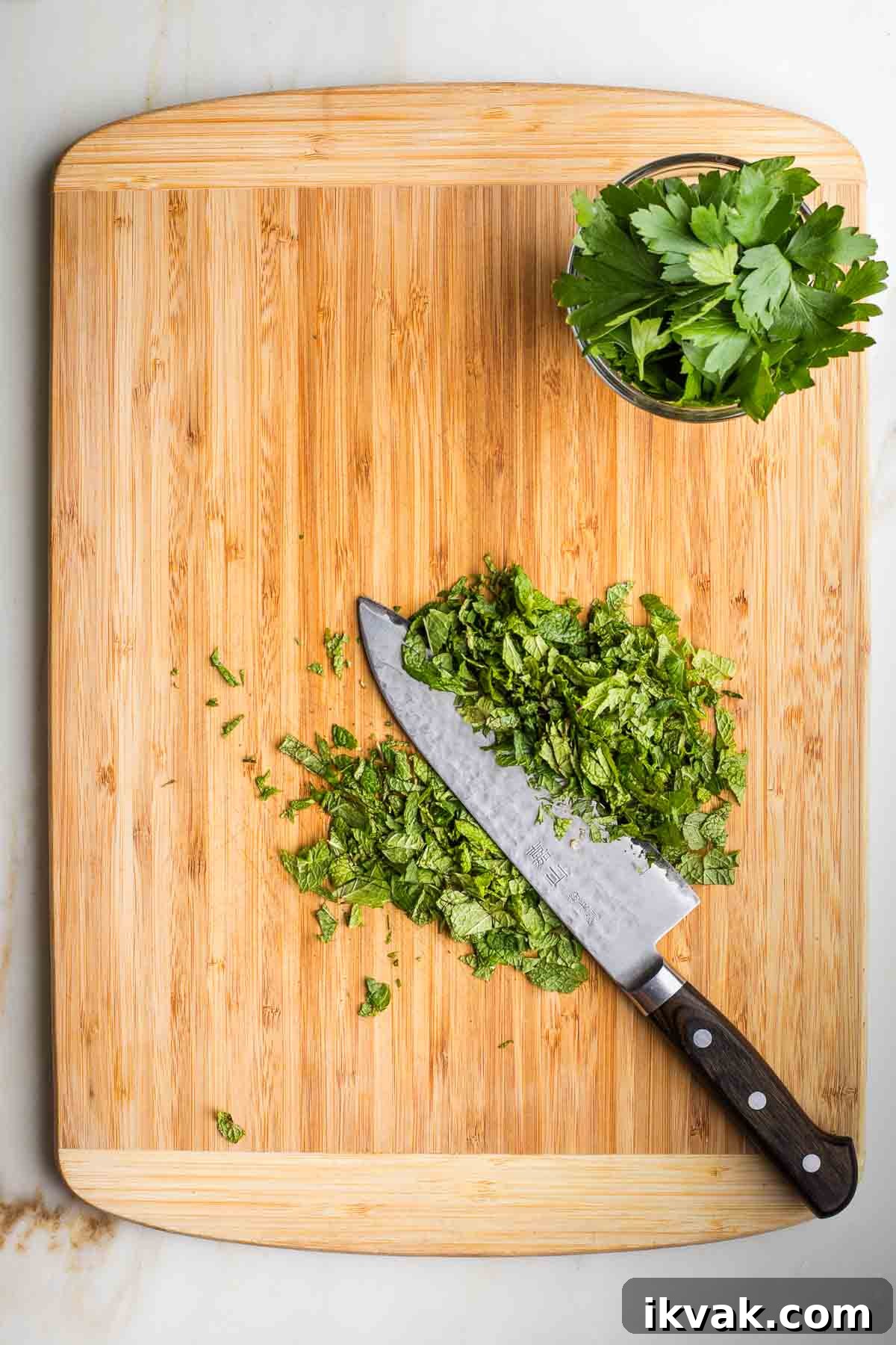 Gluten-Free Tabbouleh with Roasted Parsnips 7 Stack of fresh mint leaves being sliced thin and a small dish with fresh parsley leaves.