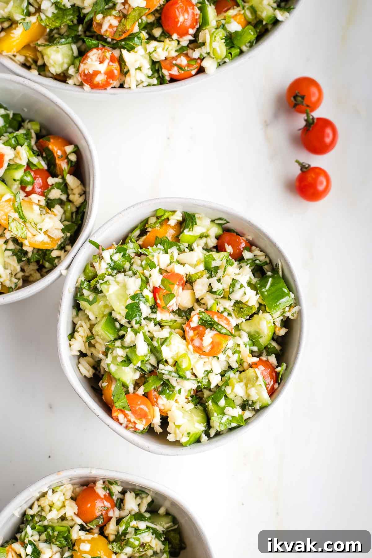 Gluten-Free Tabbouleh with Roasted Parsnips 13 Small bowls filled with colorful tabbouleh and three small cherry tomatoes on the counter.
