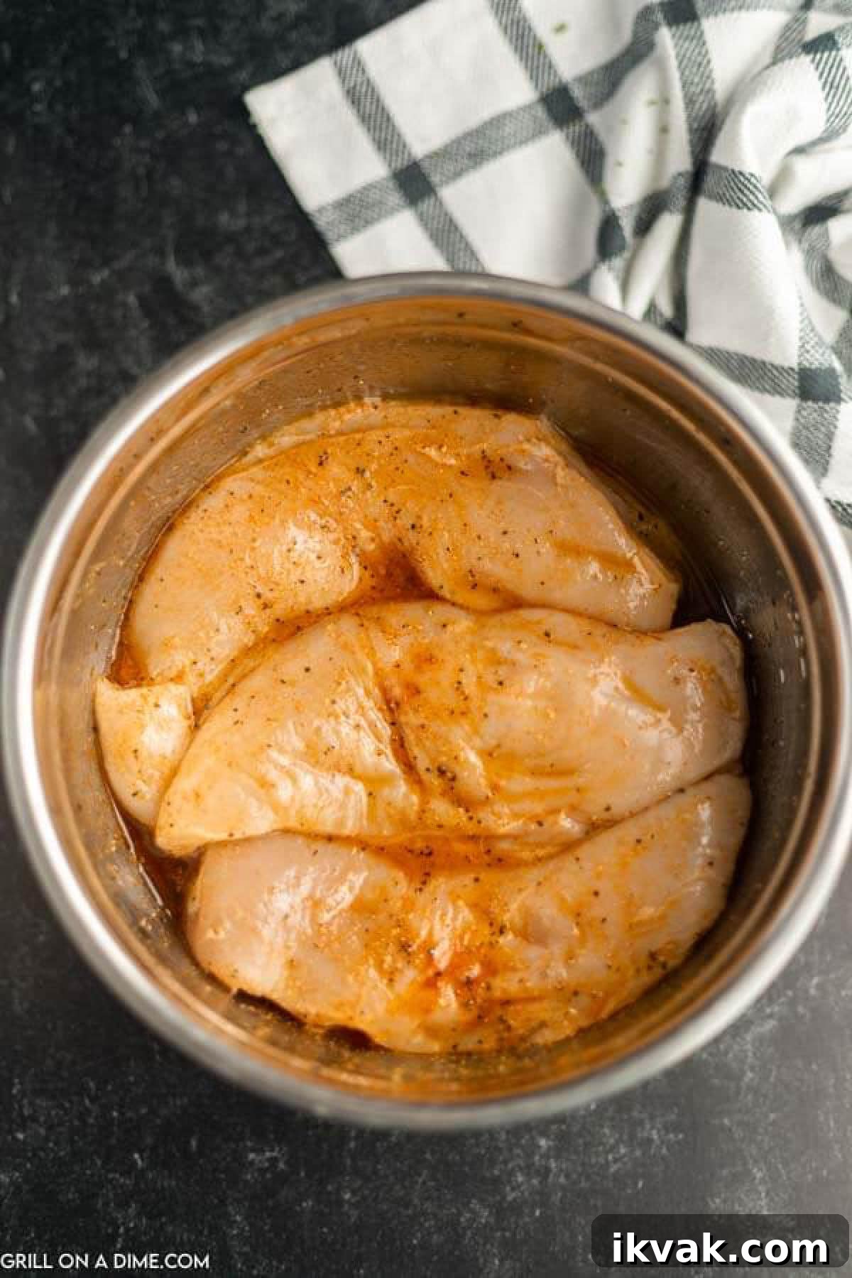 Chicken Breast in a bowl with sauce and spices spread over the chicken.