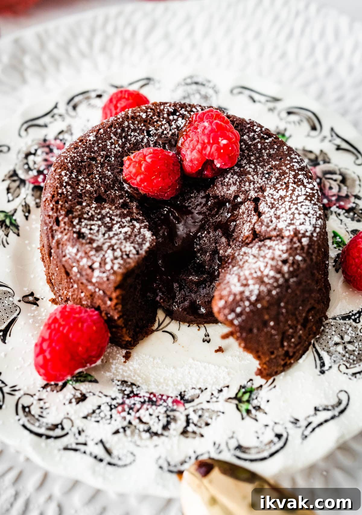 Serve the chocolate lava cakes on a plate with berries, if desired. A bite taken out and the molten center spilling out.