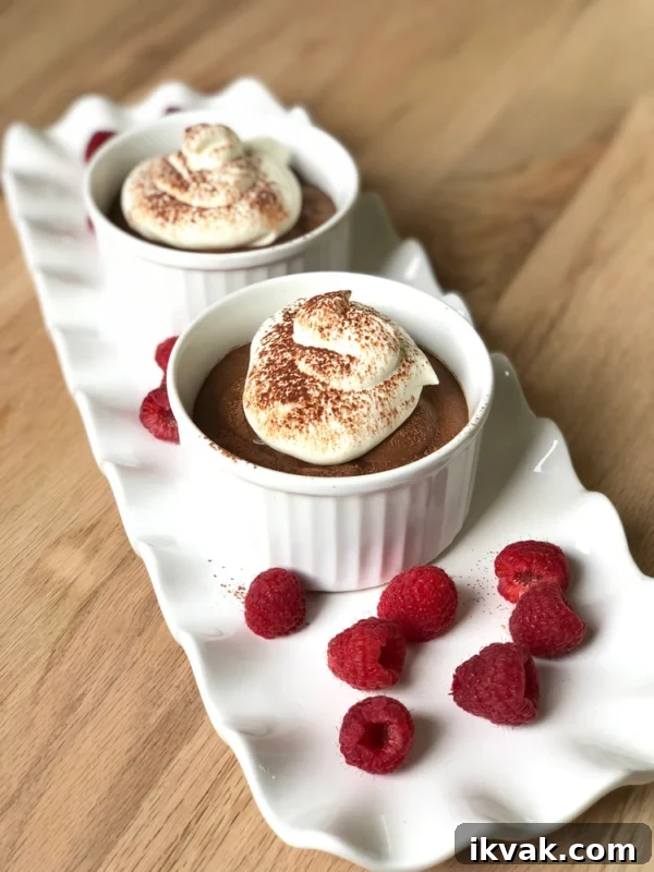 Small bowls of chocolate mousse on a long white tray.
