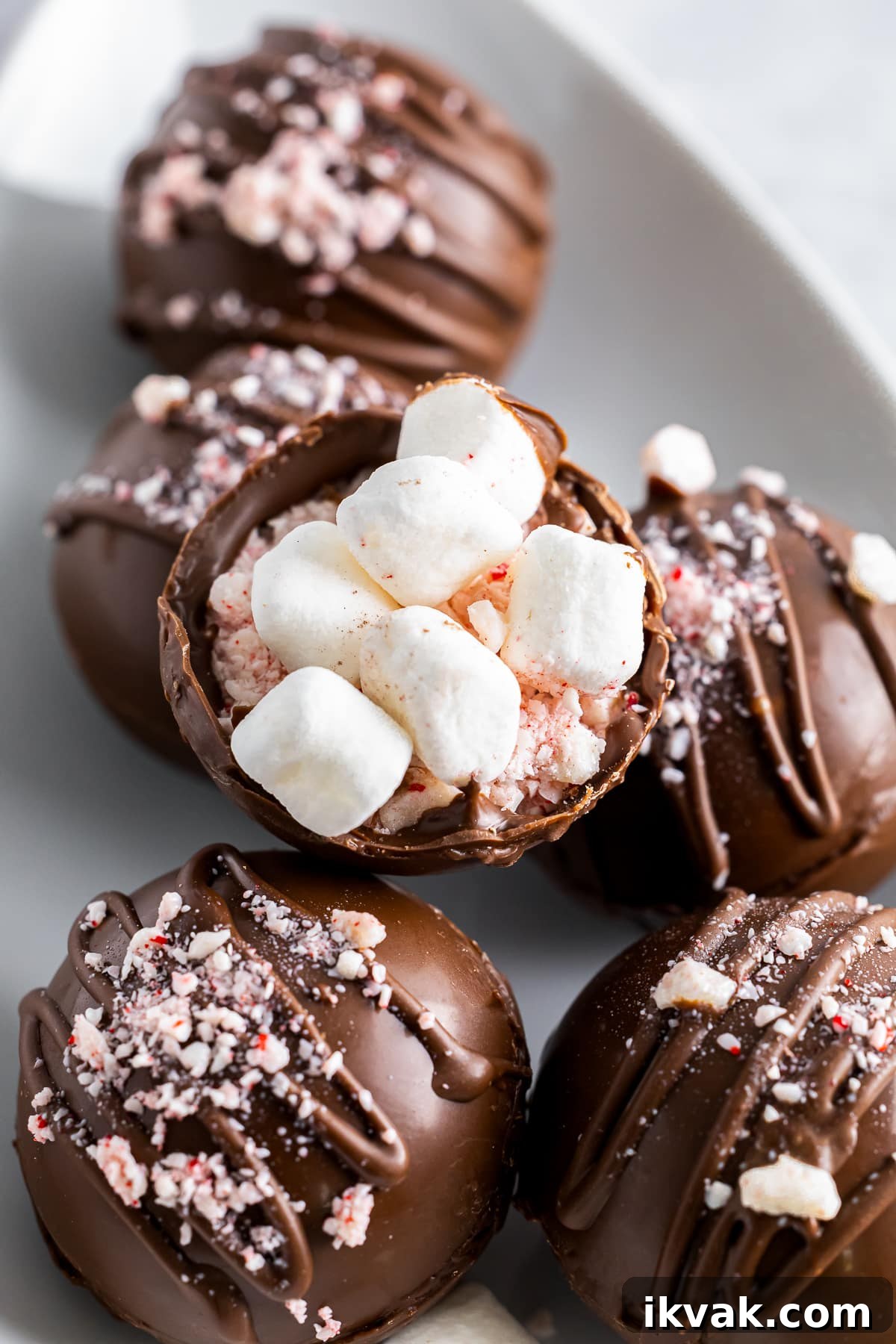 DIY Hot Cocoa Bombs Recipe: How to Make Chocolate-Filled Cocoa Bombs 3 easy cocoa bombs recipe on a white plate showing the inside of the bomb