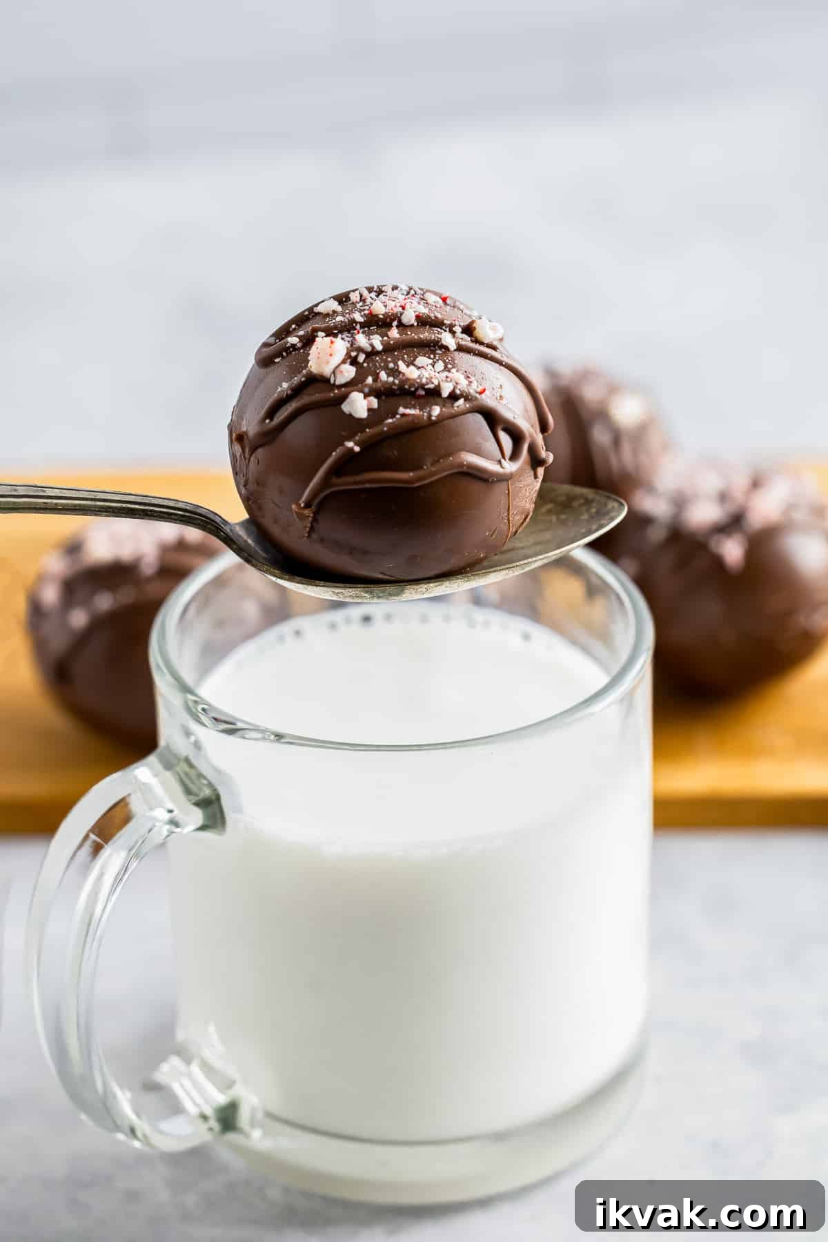 DIY Hot Cocoa Bombs Recipe: How to Make Chocolate-Filled Cocoa Bombs 8 a spoon holding a hot cocoa bombs recipe over a mug of milk