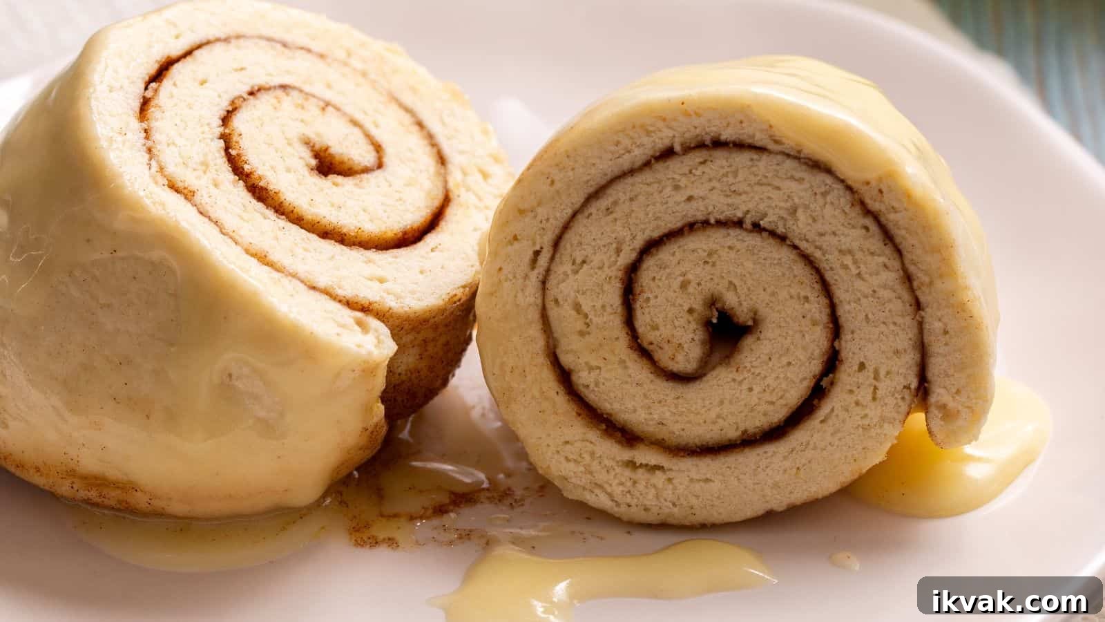 11 Mess-Free Mug Cake Recipes for Quick Single-Serve Desserts 11 Two slices of cinnamon roll cake covered in creamy frosting, placed on a white plate with extra drizzle of sauce.