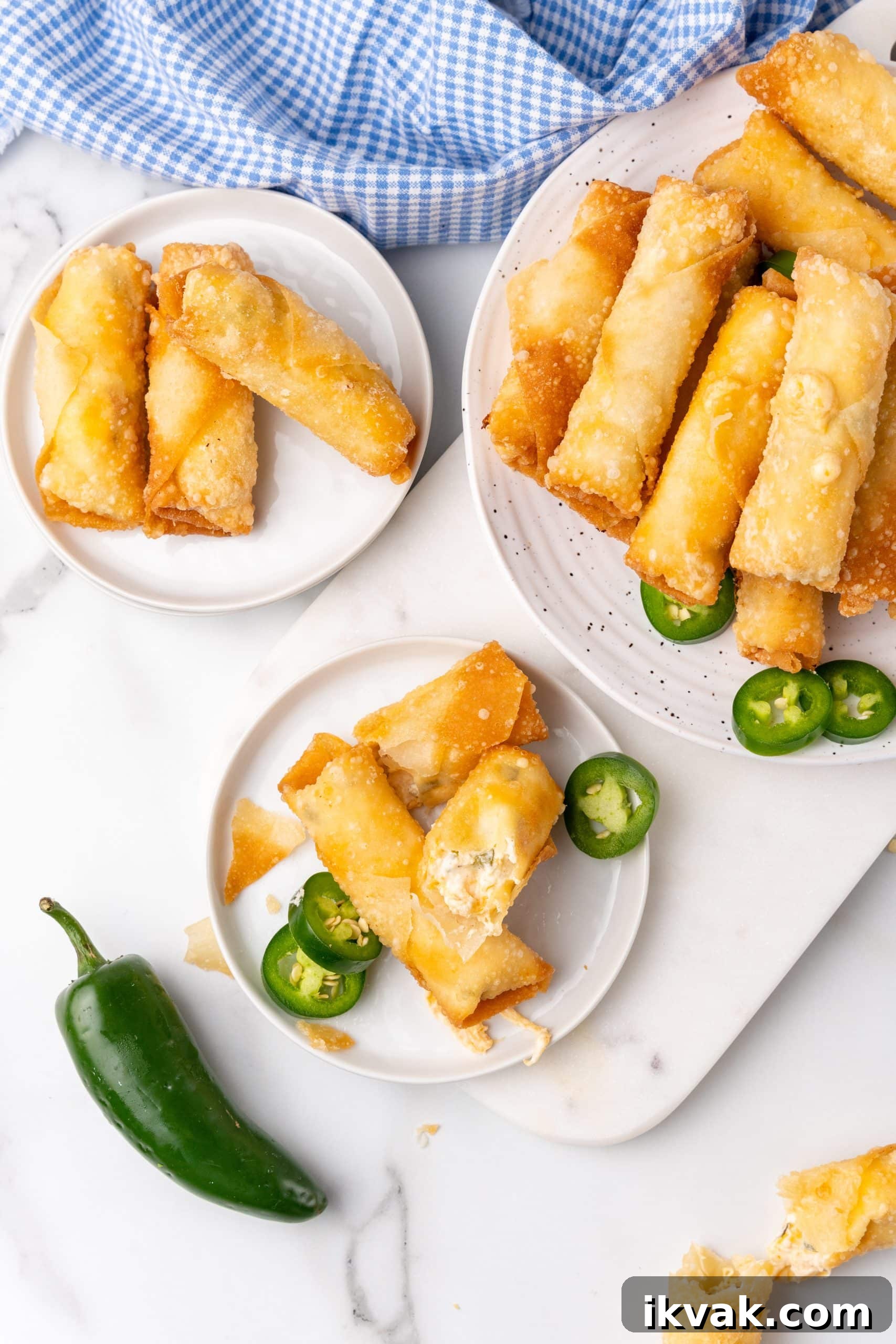 Jalapeño Popper Egg Rolls Recipe — Crispy Stuffed Jalapeño Rolls 2 jalapeno popper egg rolls stacked on small white plates