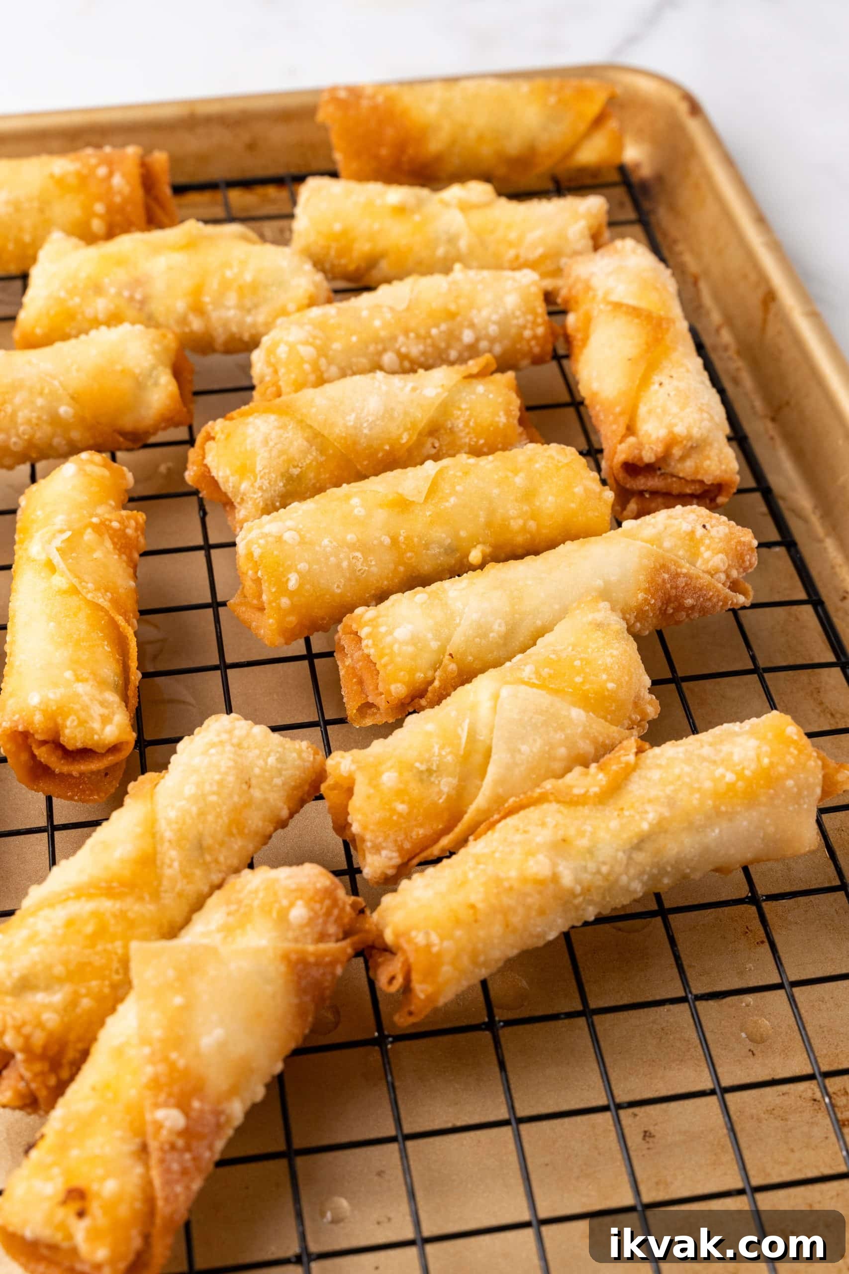 Jalapeño Popper Egg Rolls Recipe — Crispy Stuffed Jalapeño Rolls 7 crispy fried homemade egg rolls resting on a wire rack