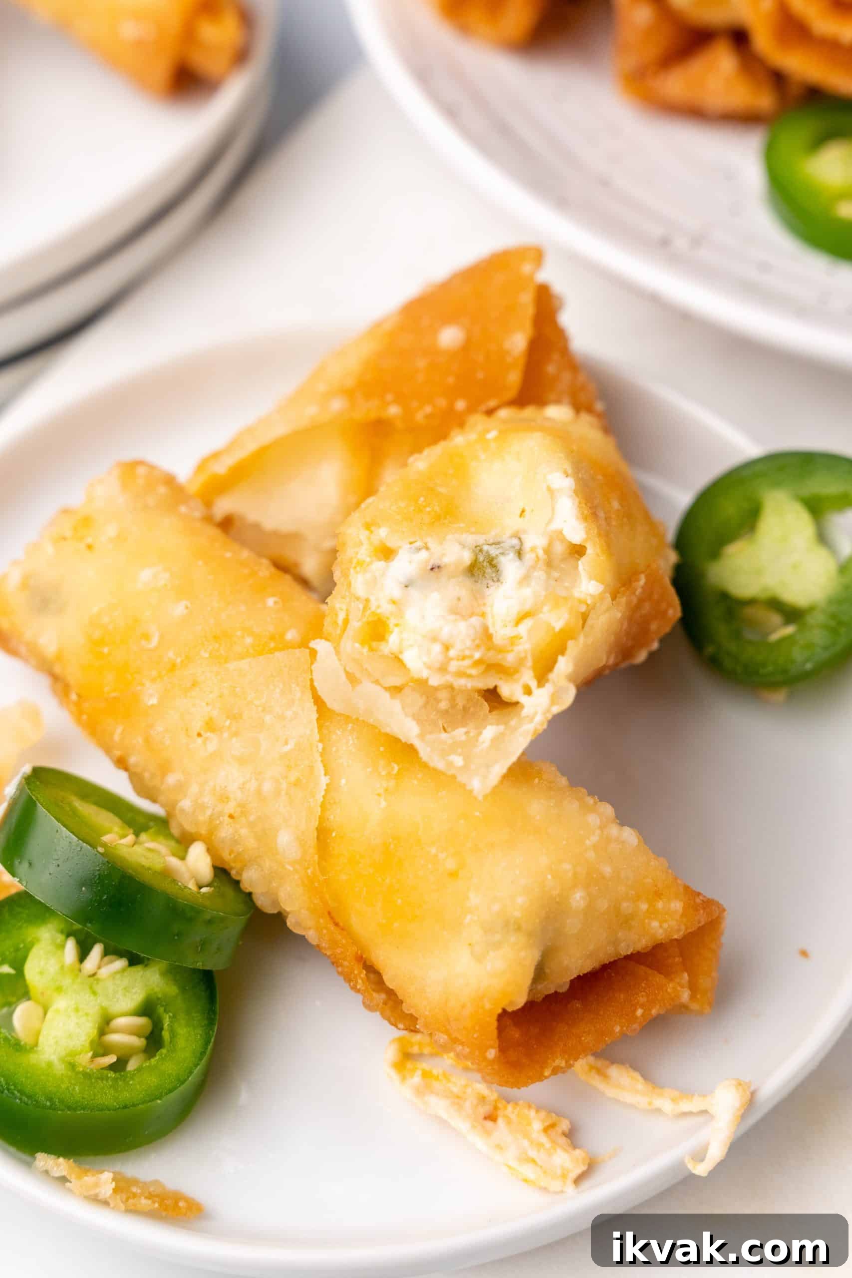 Jalapeño Popper Egg Rolls Recipe — Crispy Stuffed Jalapeño Rolls 8 jalapeno popper egg rolls stacked on small white plates