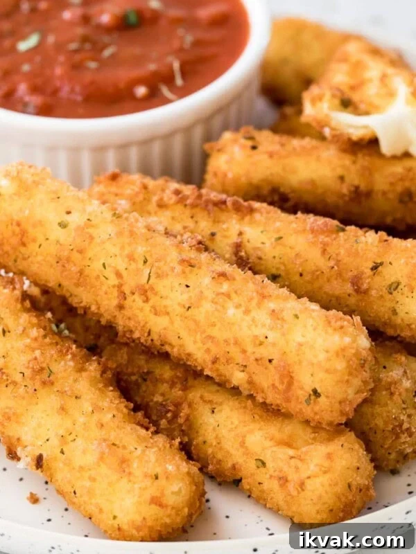 Homemade mozzarella sticks and marinara sauce on plate.