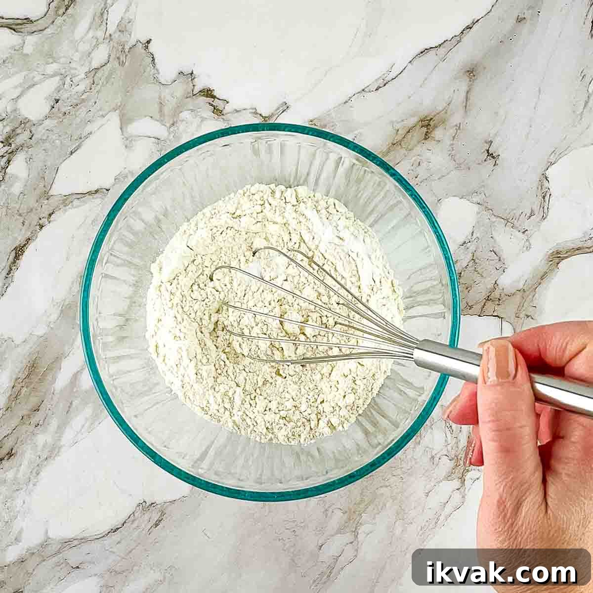 Lemon Drop Cookies Recipe: Soft, Chewy Cookies Like Panera 4 A hand using a whisk to combine the dry ingredients in a mixing bowl.