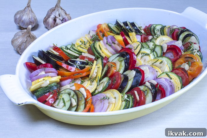 The vegetables layered in an oval baking dish ready to roast in the oven