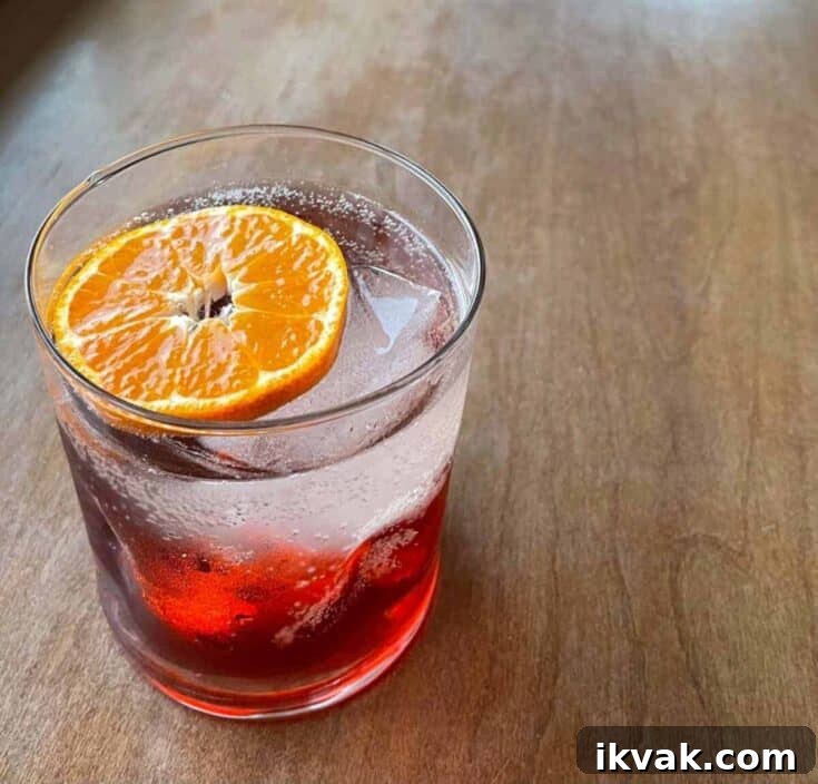 A negroni spritz in a lowball glass garnished with an orange slice.
