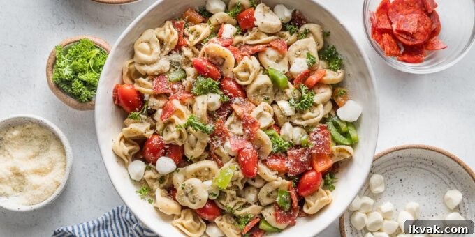 Close up of a bowl full of tortellini pasta salad loaded with peppers, pepperoni, tomatoes, mozzarella, and Italian dressing.