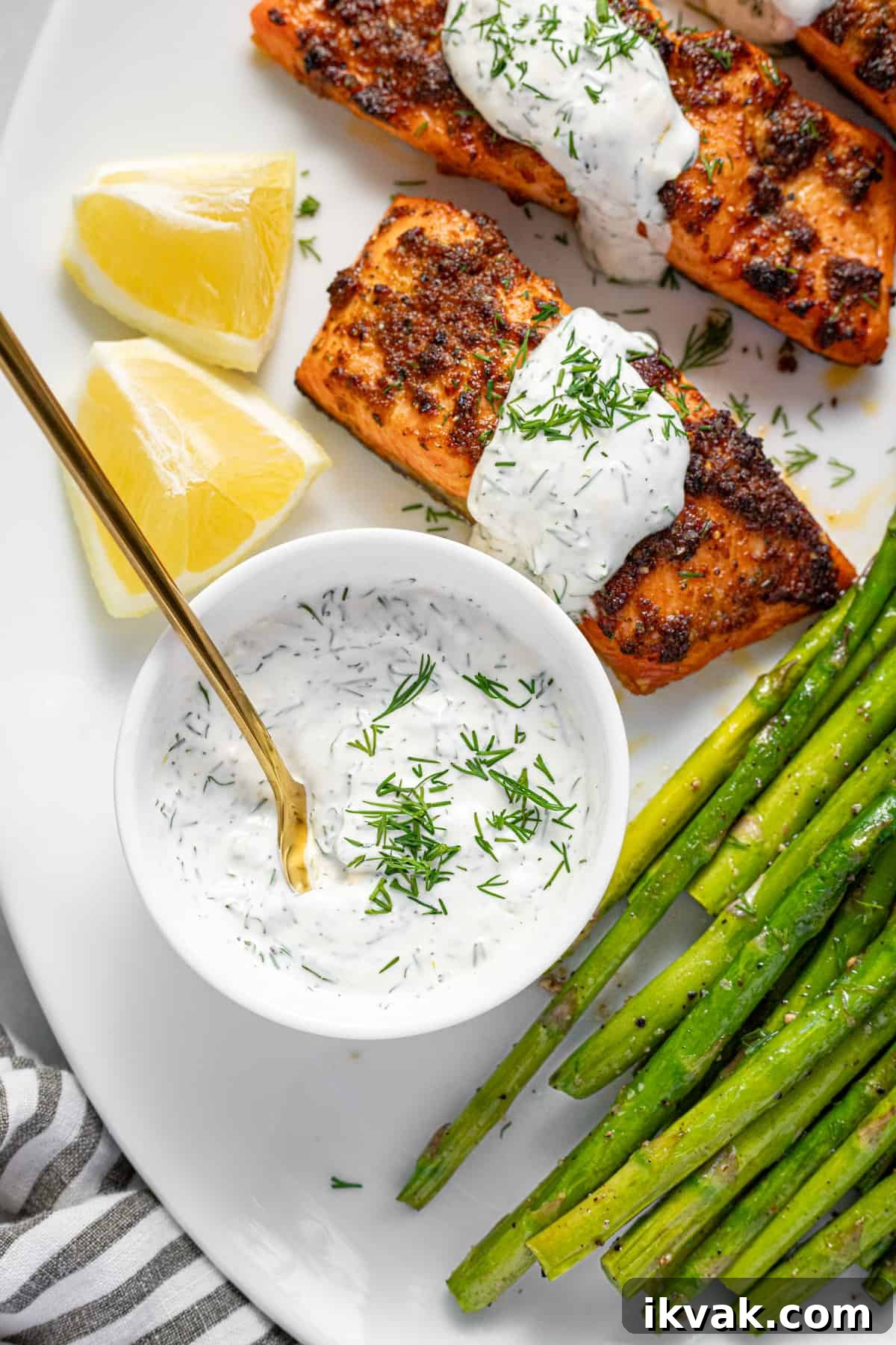 Creamy Dill Sauce for Salmon in 5 Minutes 2 Small white bowl of homemade creamy dill sauce on a platter with salmon and veggies.