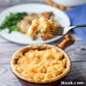 Ultimate Creamy Baked Mac and Cheese Recipe 9 A forkful of cheesy macaroni over a crock filled with it